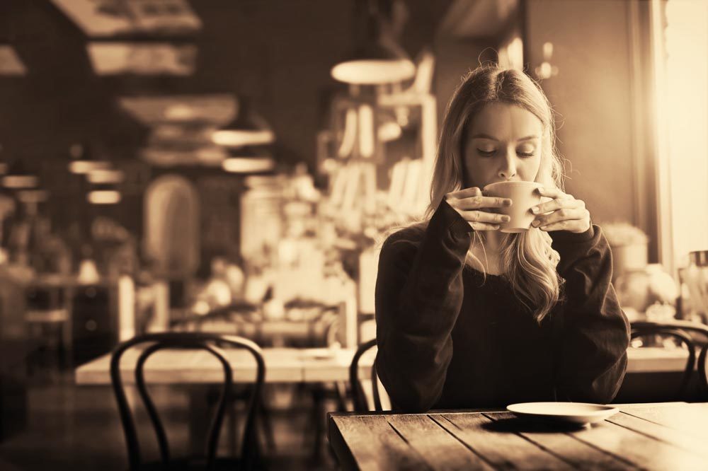 Girl sitting at the bar drinking a cafe